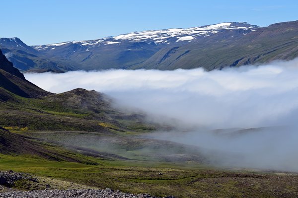 Bij een pas in Oost IJsland hangen wolken als een deken in het dal