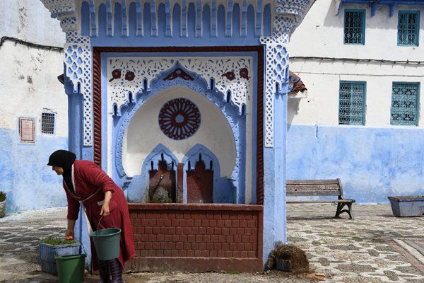 Vrouw haalt water in Chefchaouen, Marokko