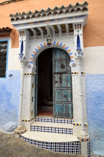 Oude blauwe deur in rijk versierd portiek in Chefchaouen, Marokko