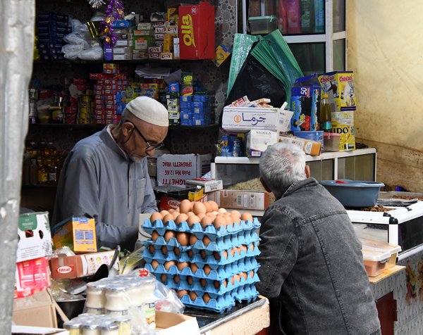 Levensmiddelenverkoper bij loket met klant in Fez, Marokko