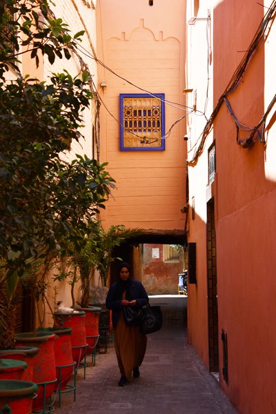 Vrouw in smal straatje met poort in Marrakesh, Marokko