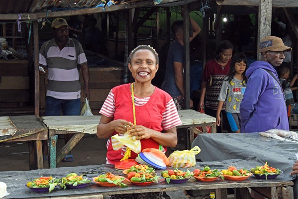 Vrolijke koopvrouw met groente op de markt van Sorong, Papoea
